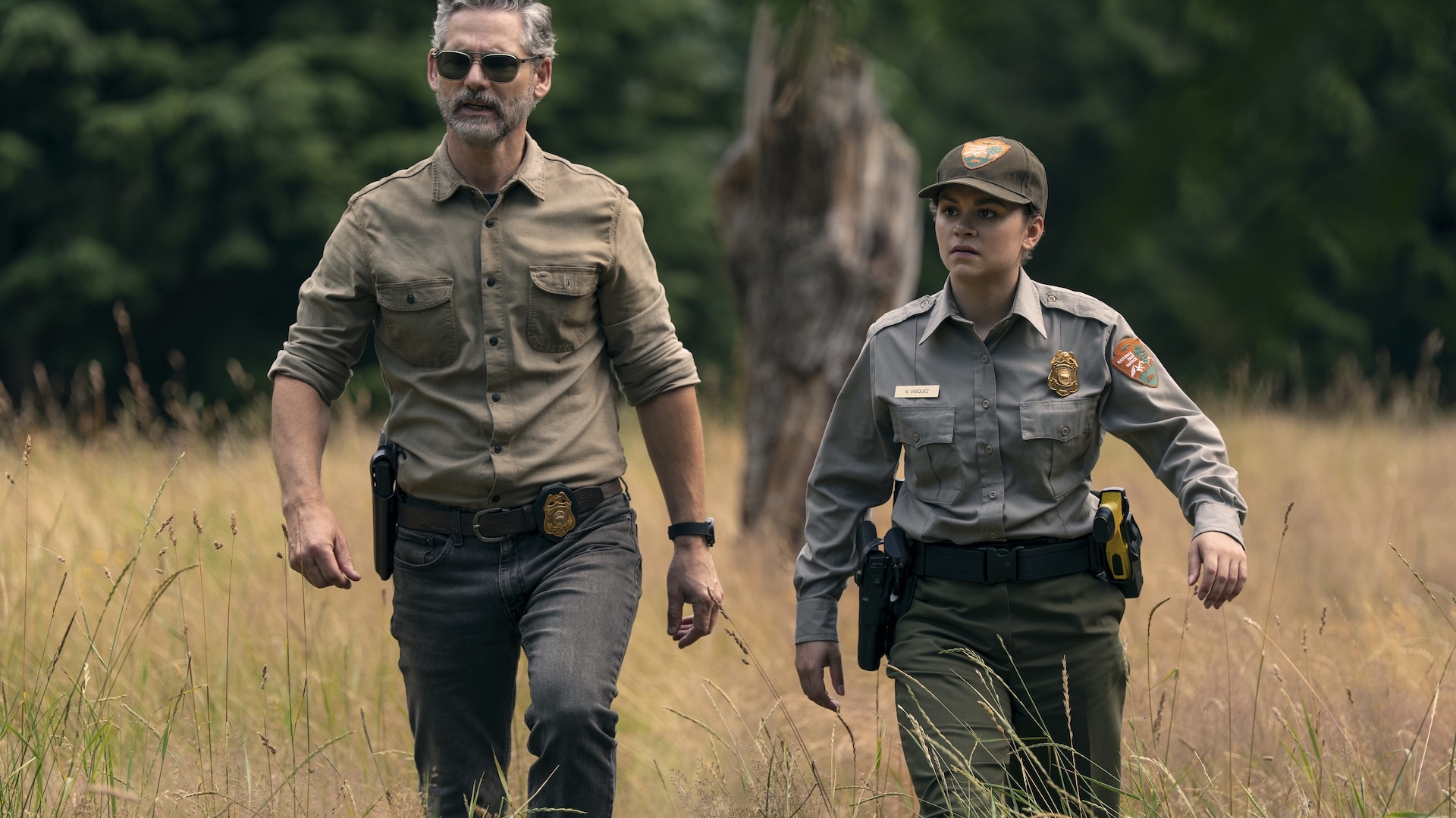 Two park rangers walking through long grass in Untamed