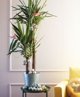 An indoor palm plant decorated with baubles and faux bird decor