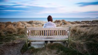 Person sitting on bench looking at ocean