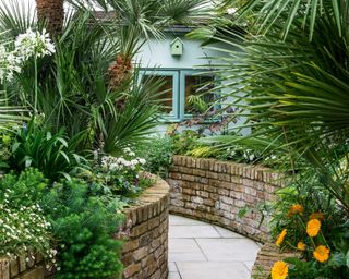 tropical garden with winding path and low brick walls