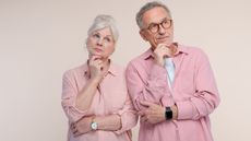 An older woman and man both appear thoughtful as they look into the distance.