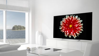 LG OLED TV mounted on a wall in a spacious living room with white painted walls