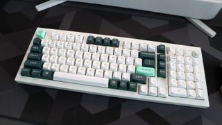 A Keychron Q5 HE gaming keyboard on a desk with white and blue keycaps.