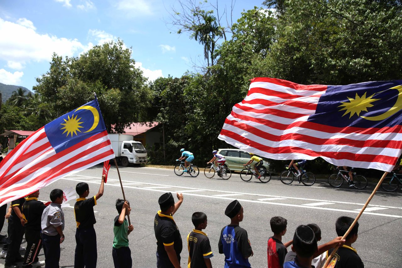 Malayian flags fly as the peloton ride by