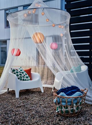 Ikea net over two plastic outdoor seats with cushions, festoon lighting and honeycomb decorations