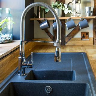 black painted kitchen with wooden worktops and black sink