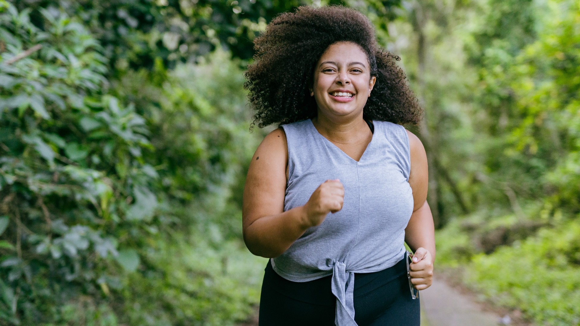 Mujer de talla grande sonriendo mientras corre en el parque