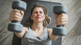 Woman lifting dumbbells above her head in chest press