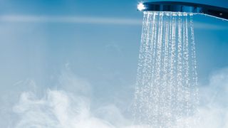 chrome shower head spraying out water and steam