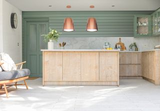 modern kitchen with wooden cabinets, green panelling and metallic island hoods