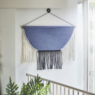 A wall with a blue and white macramé wall hanging