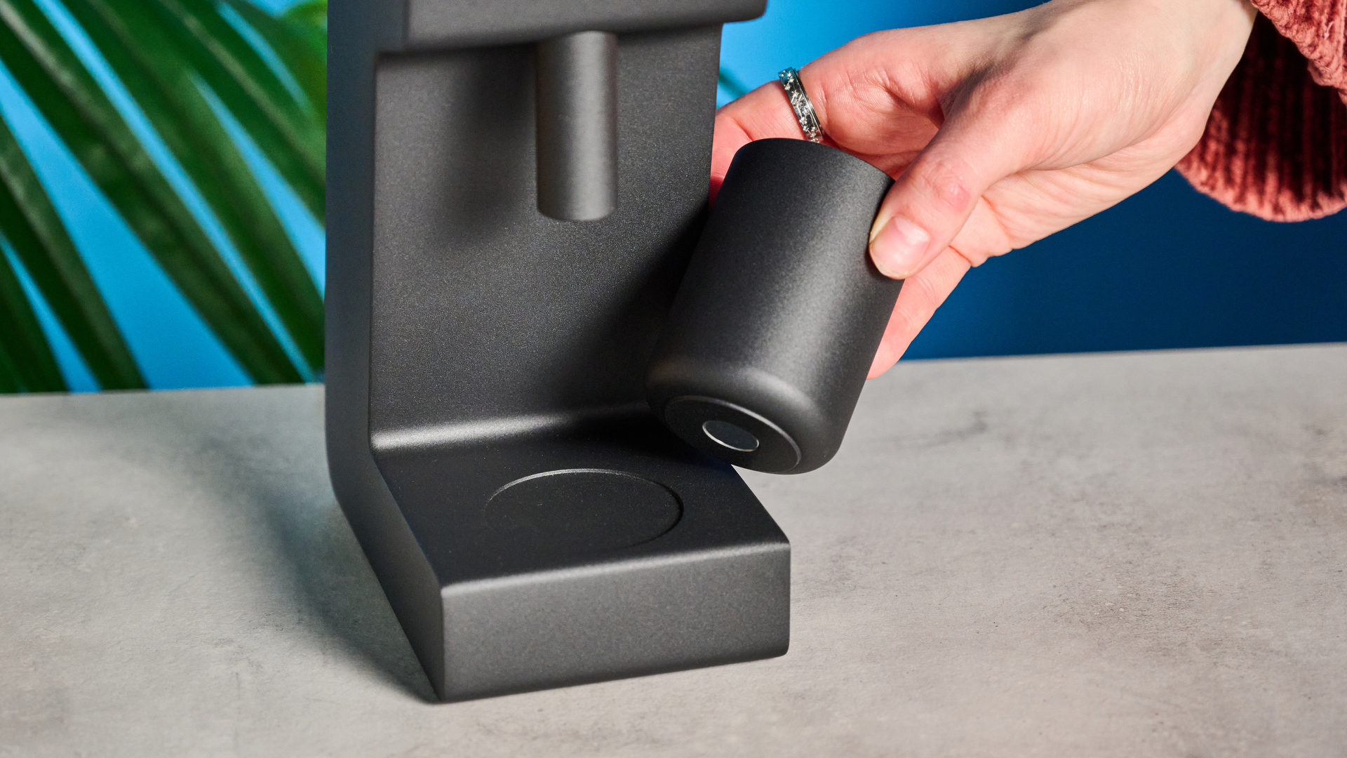 The Varia VS3 coffee grinder in use on a stone surface with a blue background