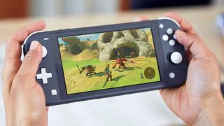 A product shot of a user playing Zelda: Breath of the Wild on a blue Switch Lite
