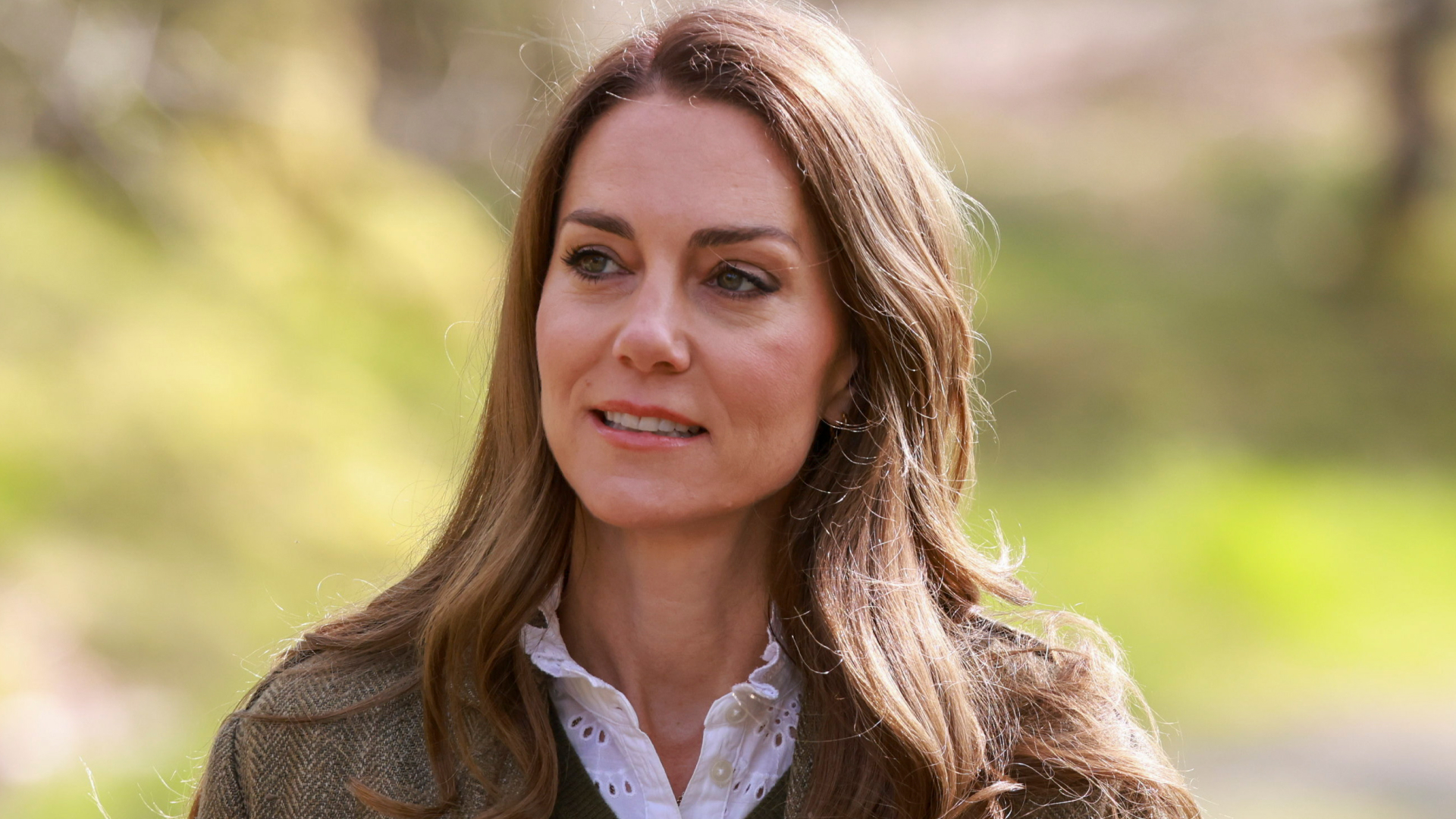 Kate Middleton wearing a green jacket with a green sweater and white shirt underneath
