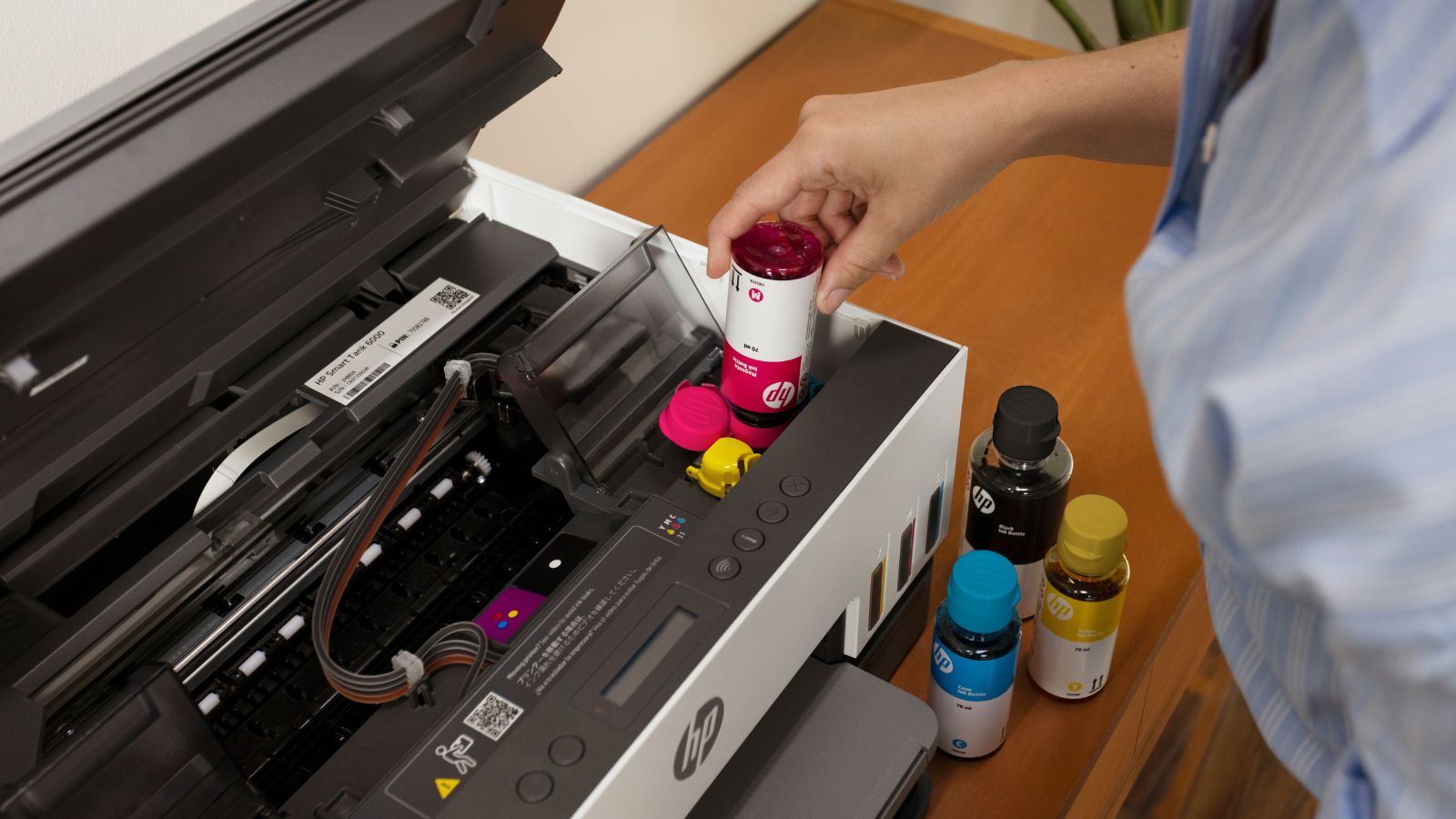 HP Smart Tank printer being refilled with a spill-free ink bottle.