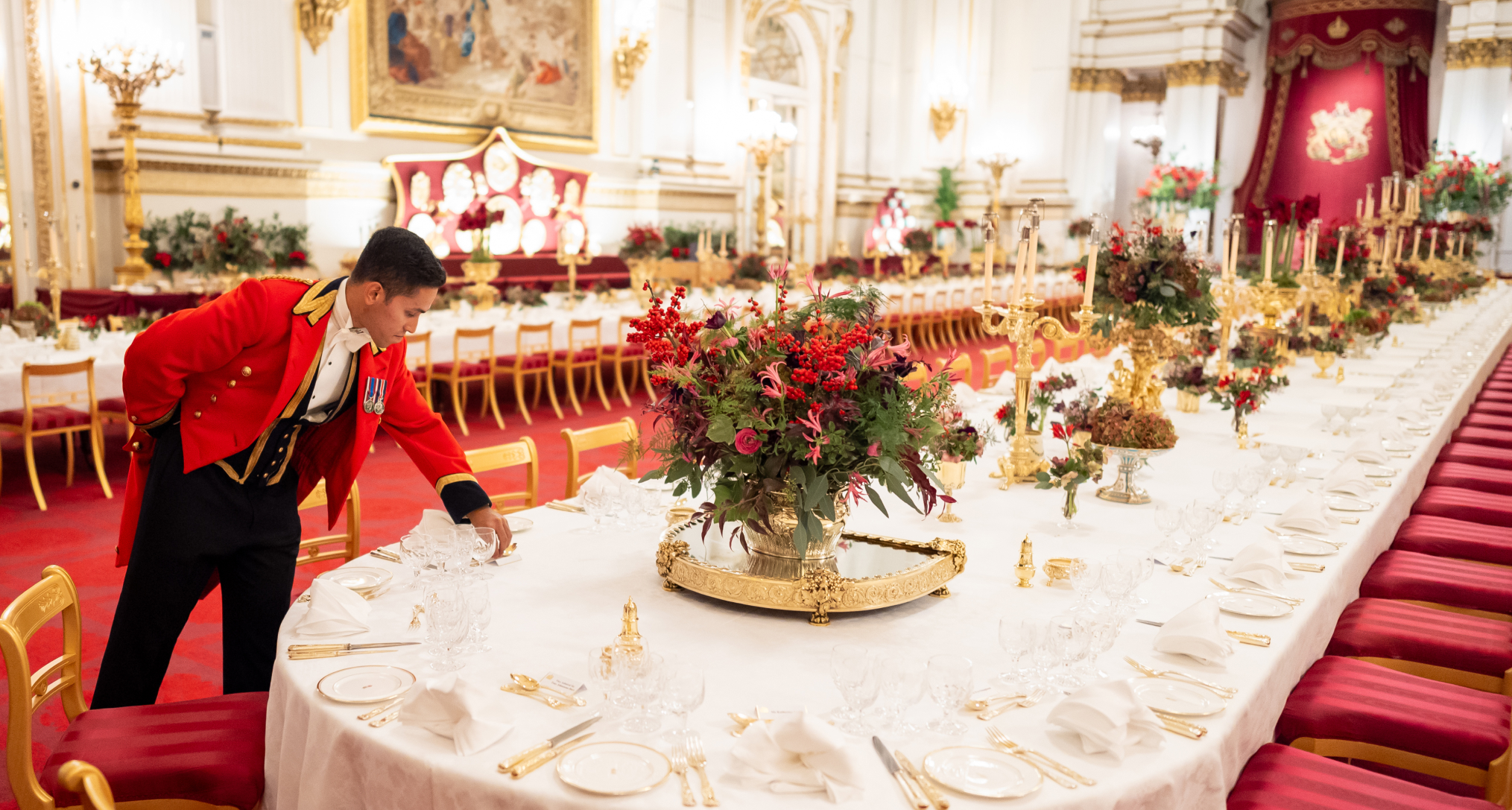 A butler fixing plates on a banquet table at Buckingham Palace