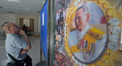 A man looks at a painting of King Bhumibol of Thailand.