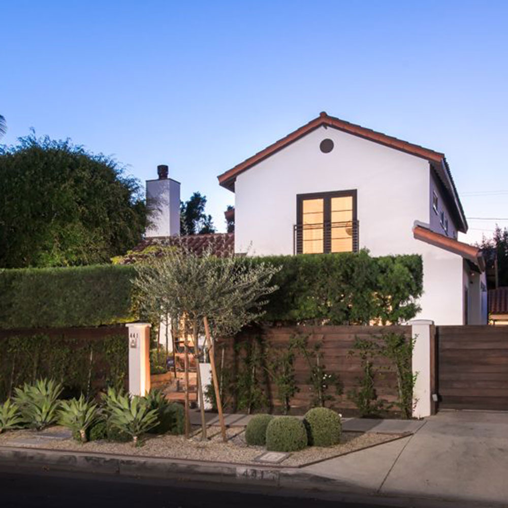 house with white wall trees and wooden door