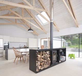 vaulted open plan kitchen and living room with exposed beams and modern stove unit