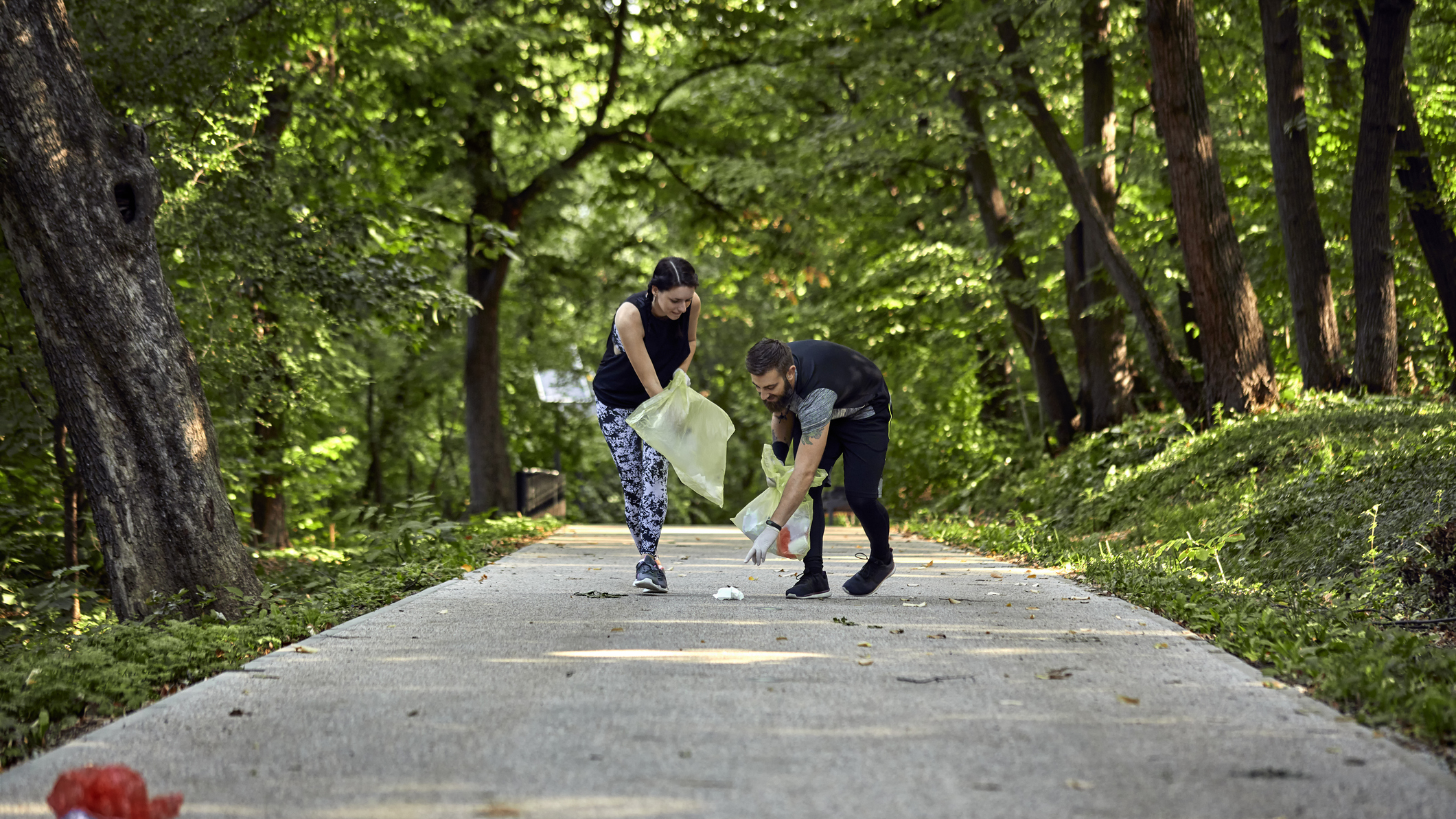 Man and woman on path in park collecting litter