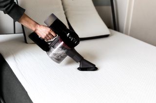 A woman vacuuming a mattress