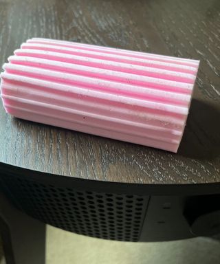 A pink damp duster sponge on the top of an air purifier table with dust in the grooves