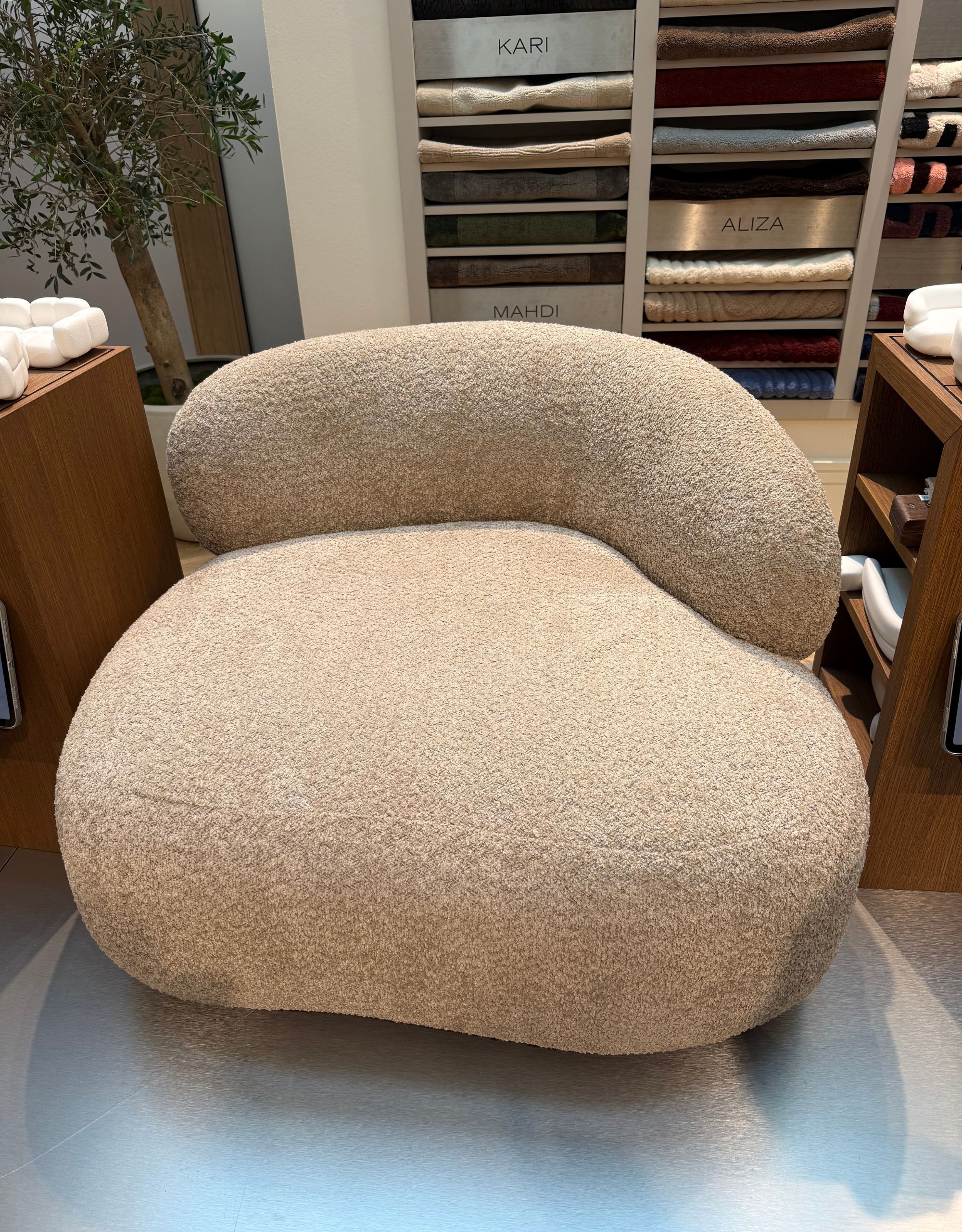 A modern curved-back armchair in front of a display unit of folded fabric swatches