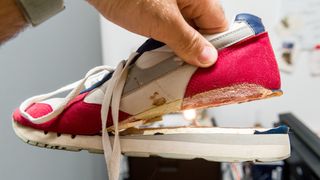 Man holding sports shoe with sole falling off