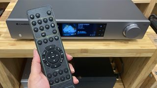 Cambridge Audio CXN100 music streamer with remote in hand