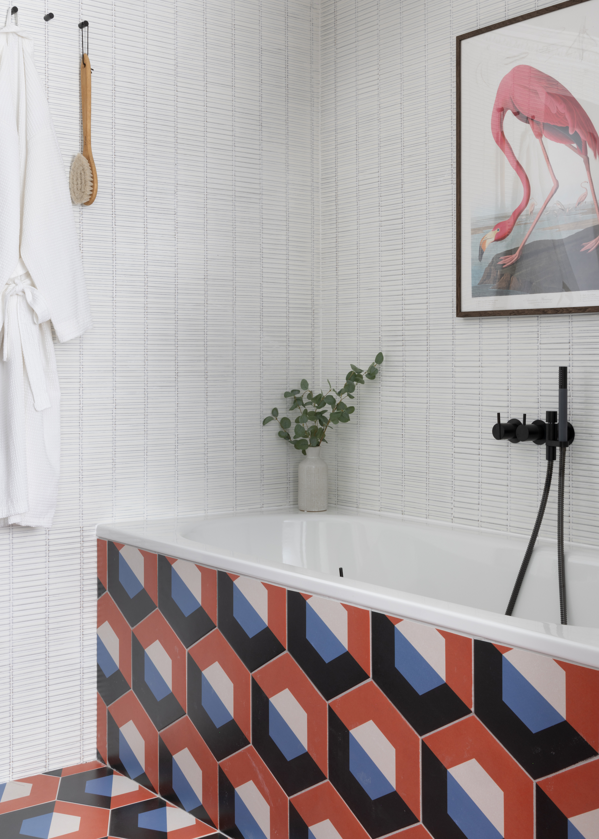 A bathtub with bold graphic tiles leading to the flooring as well as white contrasting wall tiles