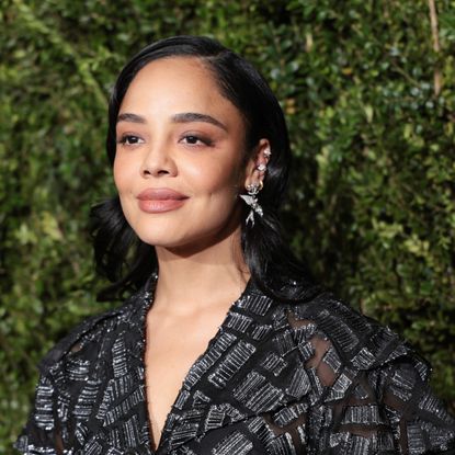 a light skinned woman with black hair photographed in front of a grassy background