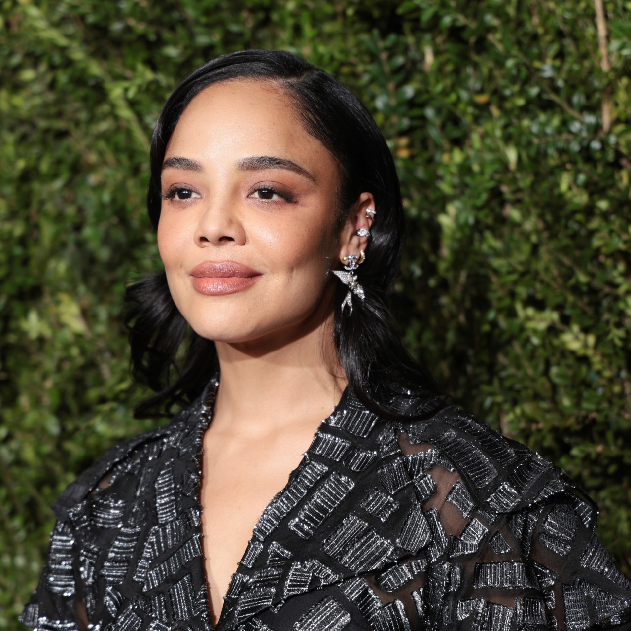 a light skinned woman with black hair photographed in front of a grassy background