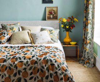 Blue bedroom with low bed with lemons on bedding and floral curtains, demonstrating how to make a small bedroom look bigger.