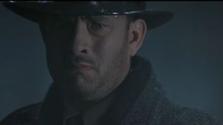 Tom Hanks stands sullen in the rain in Road to Perdition