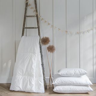 Mattress laying over a ladder shelf, with a pile of three pillows next to it