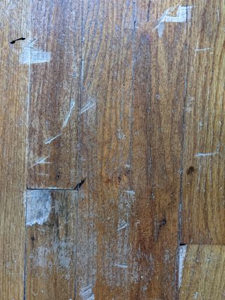 a close up of scratched discolored wood floor
