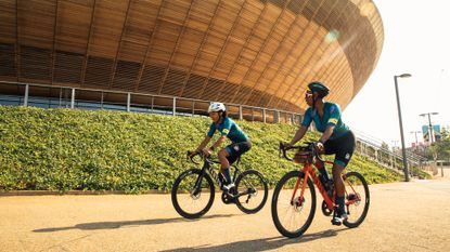 Two women round around Lee Valley Stadium in Rapha clothing 