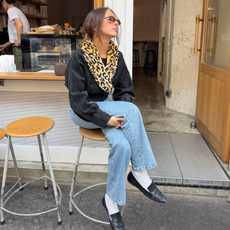 An image of an influencer wearing a black coat with a faux leopard print collar, light blue jeans and black loafers in Paris