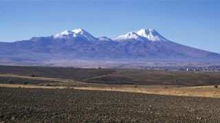 A view of snow-capped mountains over a flat landscape