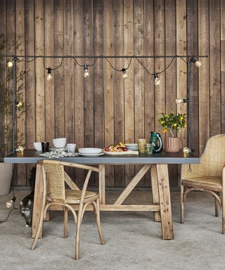 outdoor dining table and festoon light bracket against a wood panelled wall
