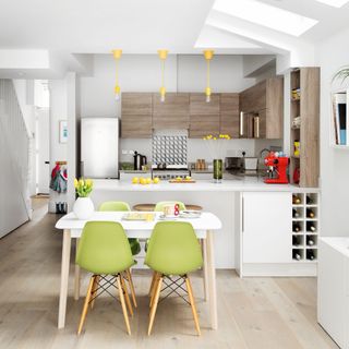 Soft white and grey kitchen with small dining table and green chairs