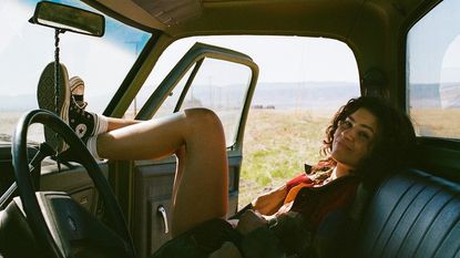 Zendaya as Rue in Euphoria season three, sat in a truck with her feet on the dashboard 