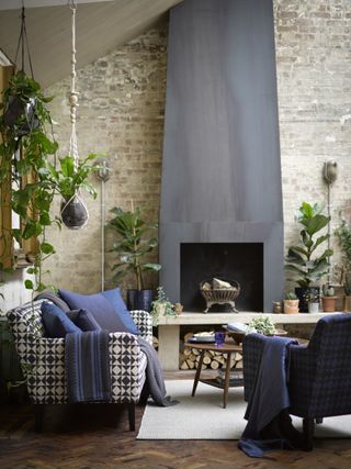 Exposed brick wall in modern living room with checked sofa, steel fire place and hanging house plants