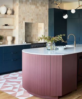 A blue and pink kitchen with fluted cabinets on the island