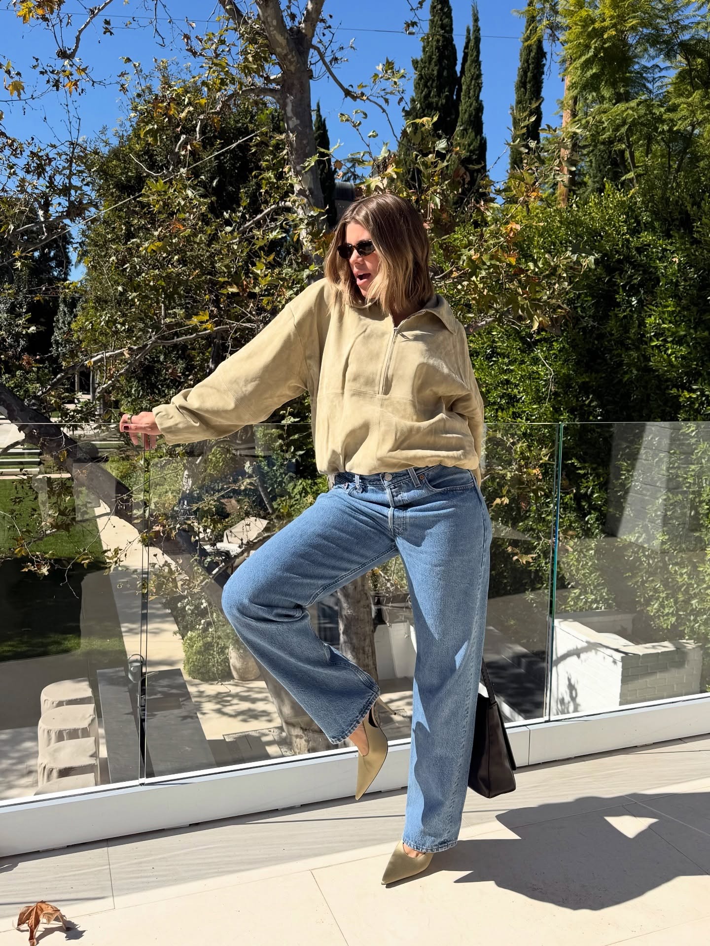 Sofia Richie wearing a suede pullover, jeans, and satin pumps