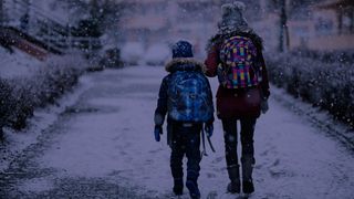 Two children walking to school on a dark winter morning