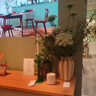 A striped vase of flowers with a candlestick on a sideboard from the John Lewis spring/summer 2025 press showcase