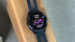 The Garmin Forerunner 970 on an armrest showing my tolerance, acute impact load miles, and actual miles in a chart.