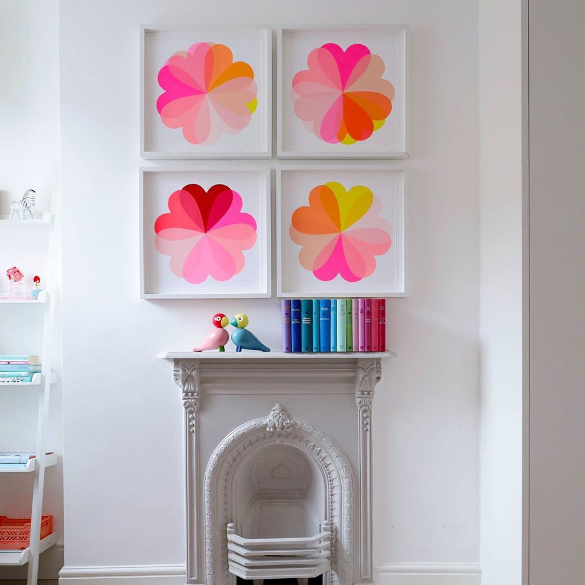 Four pink graphic artworks above white fireplace