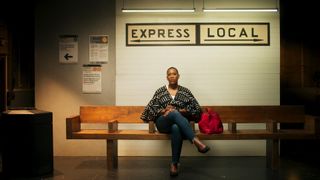 a woman (Dr. Meredith Clark) sits on a set evoking an NYC subway stop, under a sign reading "Express Local," in the docuseries 'Black Twitter: A People's History'